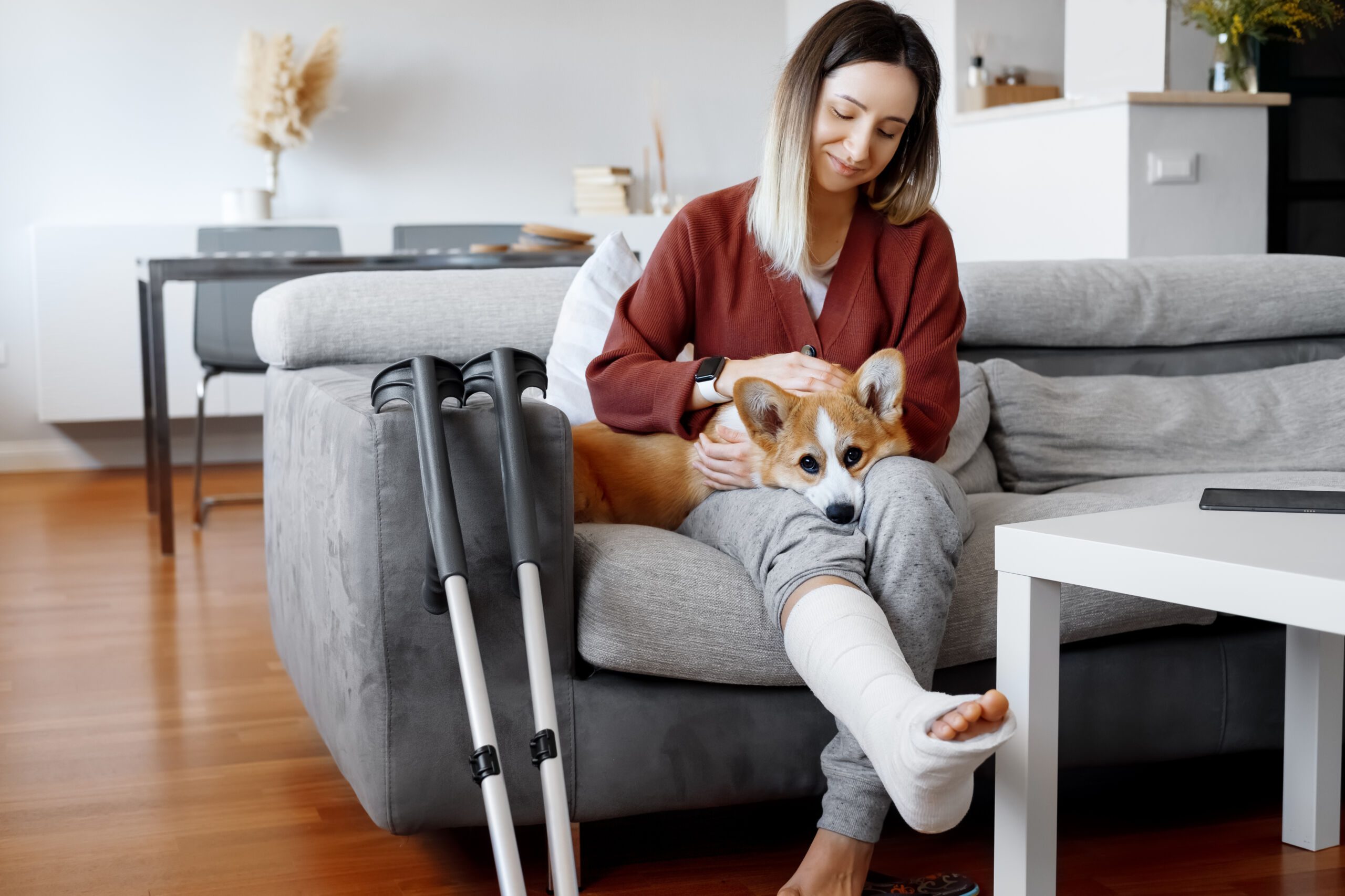 Adult woman in her late twenties on couch at home with crutches