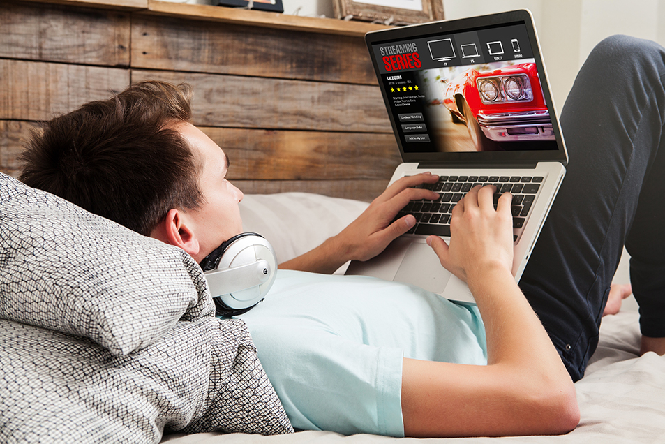 man lying down watching videos on laptop