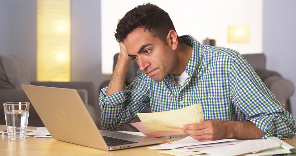 man in front of laptop frustrated with bills