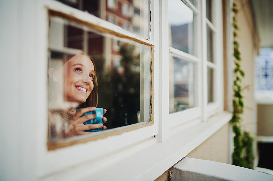 woman looking out her window smiling