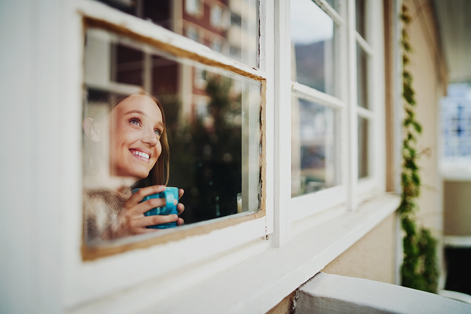 woman looking out of her window smiling