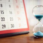 an hourglass sitting next to a calendar