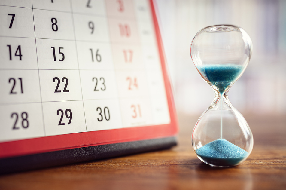 an hourglass sitting next to a calendar