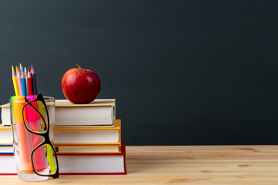 an apple sitting on top of books in front of a chalk board