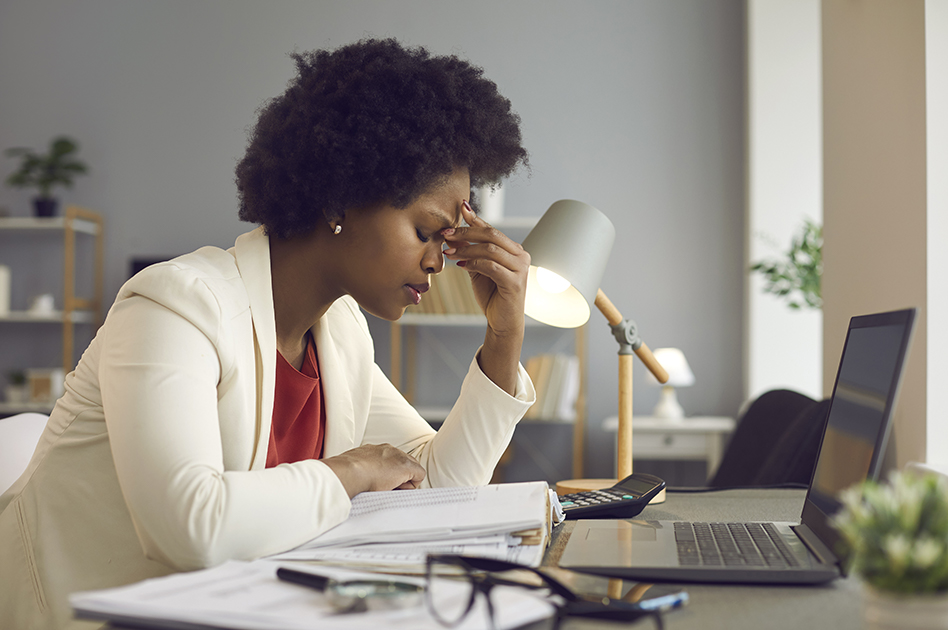 a black woman in business attire stressed in front of her computer