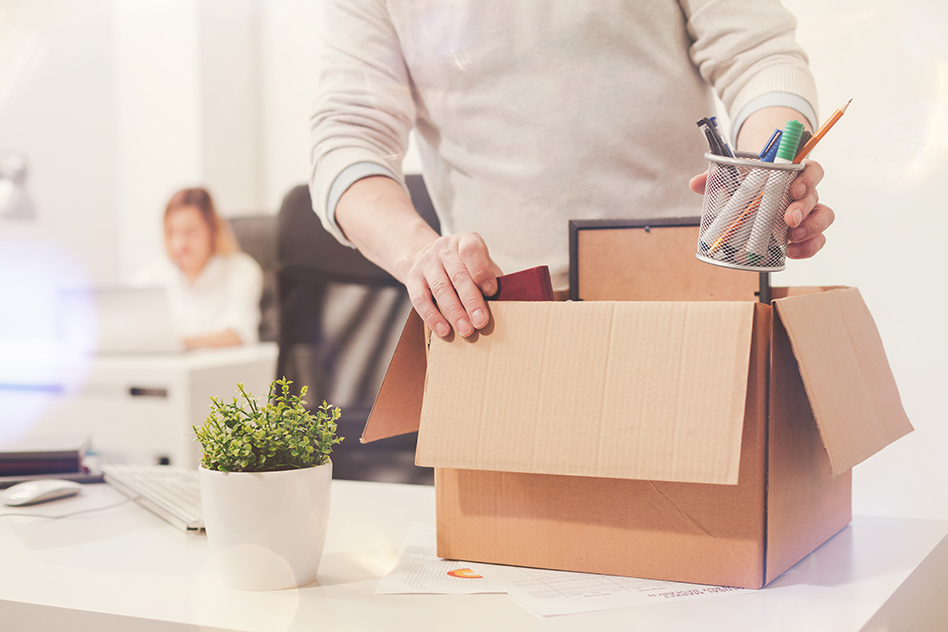 an employee in an office packing his belongings into a cardboard box