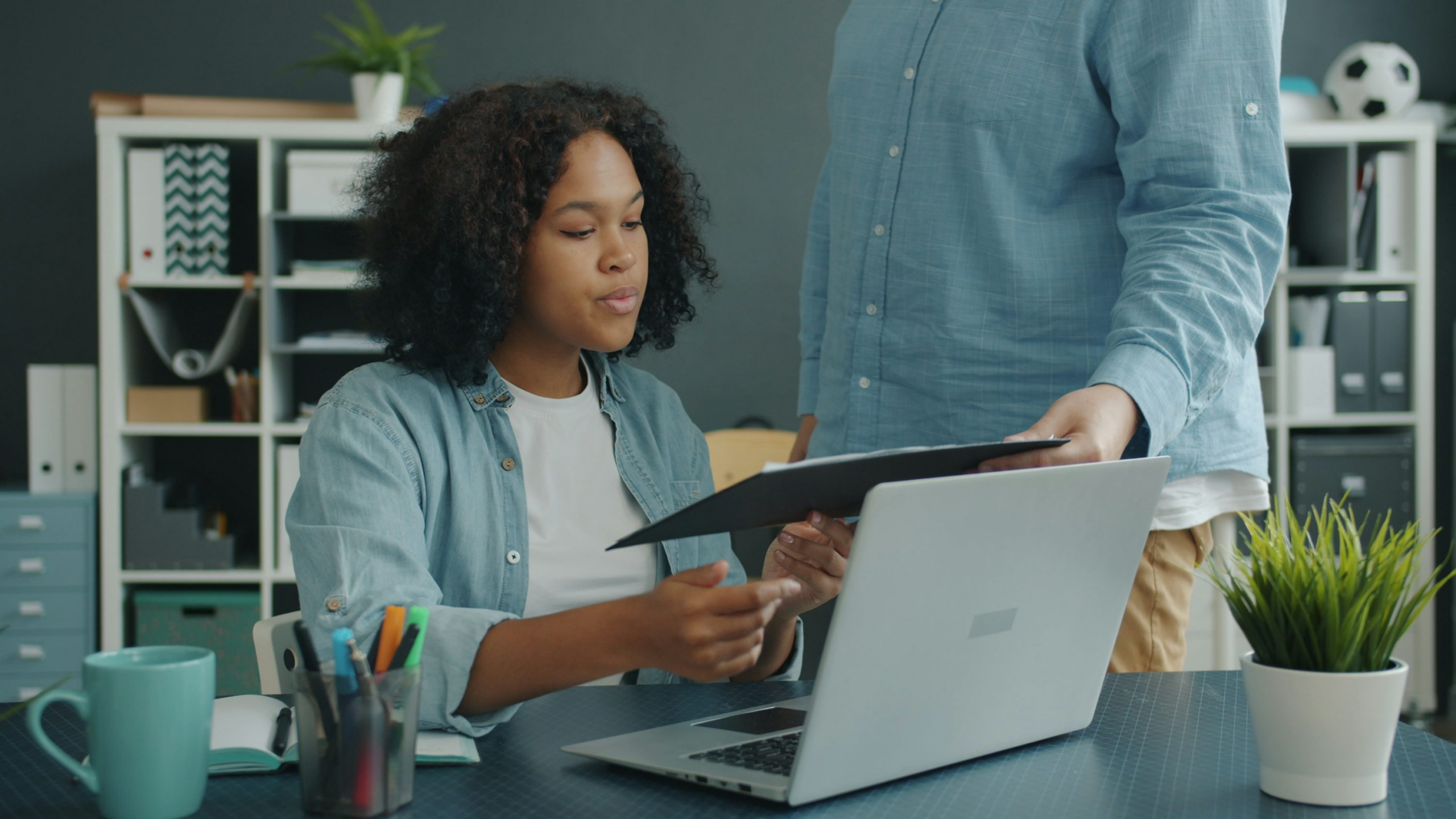 A professional employee reviews documents at an office desk with a colleague nearby, representing the federal-sector EEO complaint process and the importance of building a complete record.